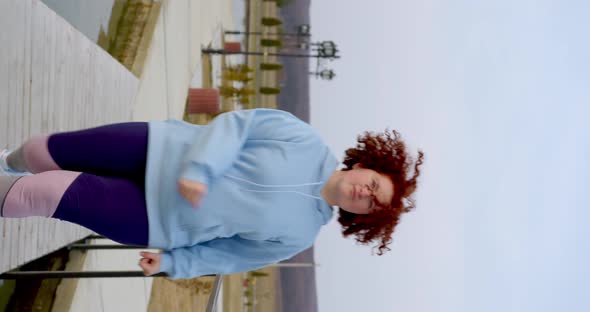 curly girl with red hair beautifully on the bridge on the lake, red hair develops