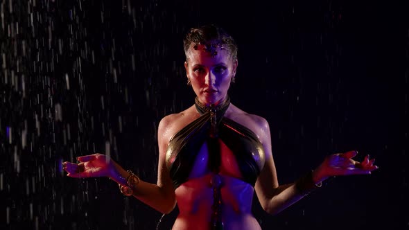 Closeup of a Woman Dancing an Oriental Dance on a Black Background in the Pouring Rain in the Studio