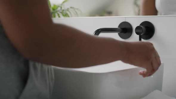 Close up of African-American person washing hands in the sink and using white towel. Shot with RED h