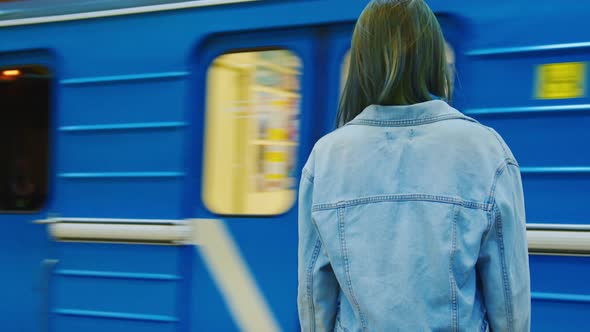 A Young Girl in a Denim Jacket is in the Subway