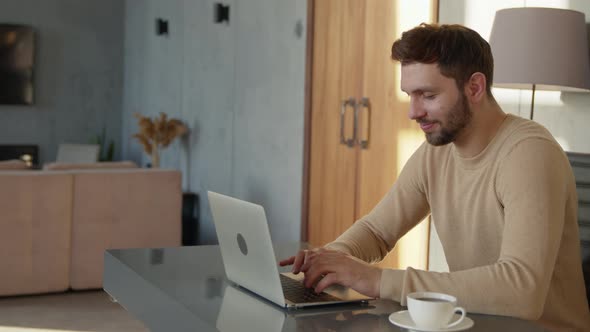 Attractive man with laptop at the desk indoors