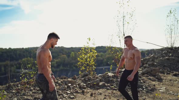 Shirtless sportsmen shaking hands in the mountains