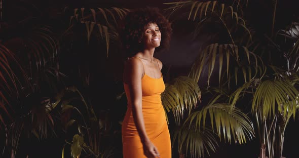 Laughing Woman With Afro Hair Dancing In Orange Dress