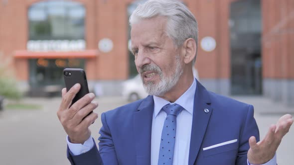 Old Businessman Upset by Loss on Smartphone