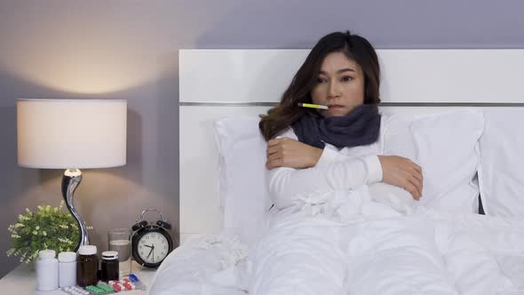 sick woman using thermometer to checking her temperature and her headache in bed