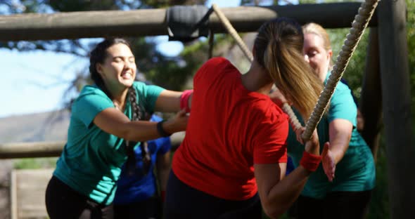 Women applauding female trainer while rope climbing