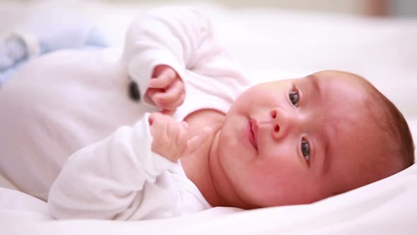 New born baby in diapers lying on a bed with blankets