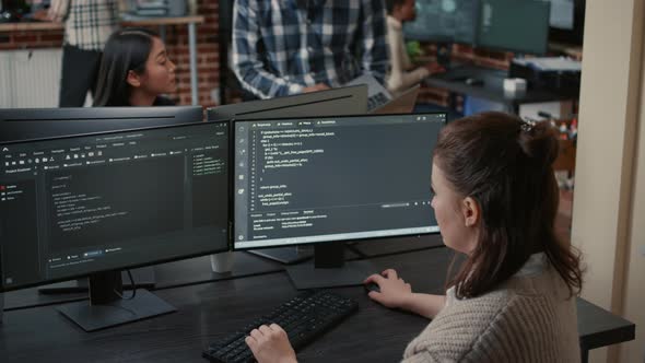 Software Programer Writing Code in Front of Multiple Computer Screens