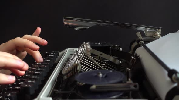 The girl is typing on a retro typewriter.