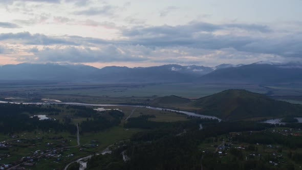 Aerial of valley in Altai and country houses under sunset sky