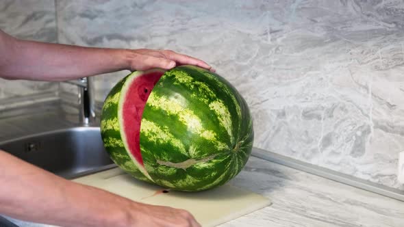 A Man Cuts a Large Watermelon with a Knife