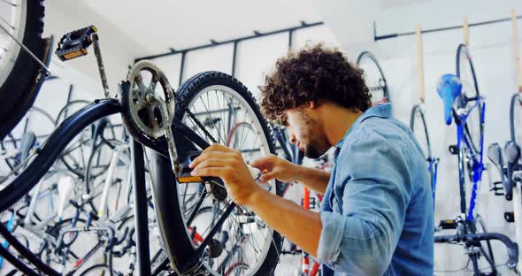 Mechanic repairing bicycle in workshop