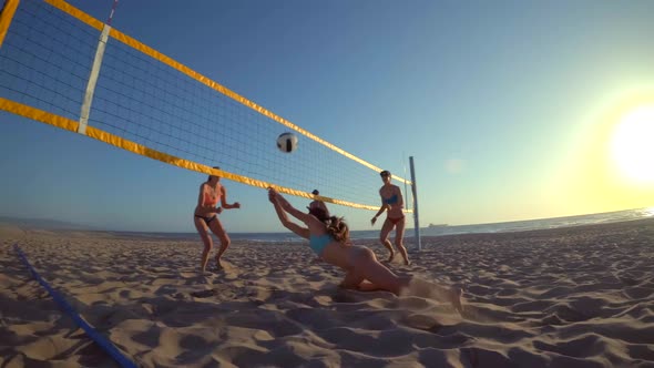 POV of women players playing beach volleyball with a girl diving to dig a ball