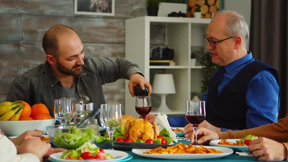 Young Man Serving His Father in Law with Red Wine