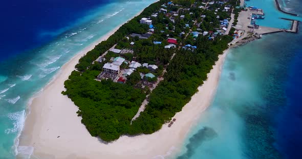 Wide flying tourism shot of a white sandy paradise beach and aqua blue water background in hi res 4K