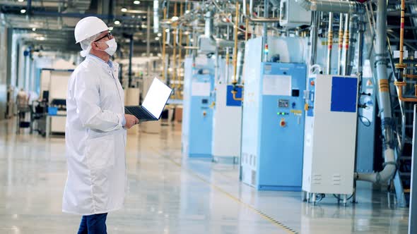 Male Engineer in a Lab Coat is Observing Factory Constructions