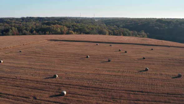 Beautiful morning flight over haystacks. The field is covered with hay.