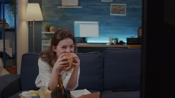 Person Watching Comedy on TV and Eating Delicious Burger