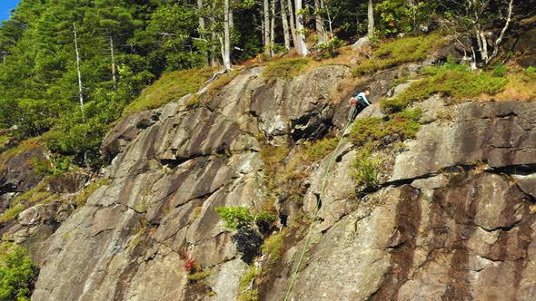 Aerial footage as Lone climber makes his way to the top of cliff in Maine