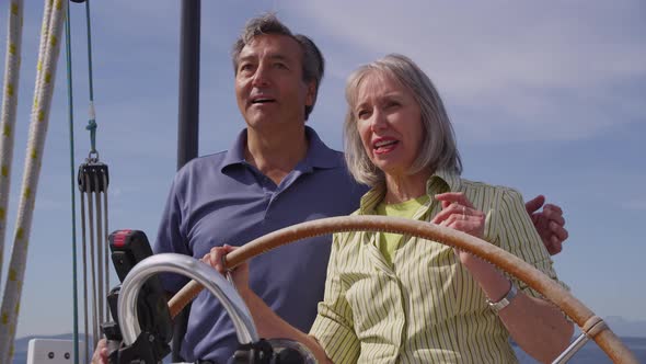 Senior couple behind the wheel of sailboat together. Shot on RED EPIC for high quality 4K, UHD, Ultr