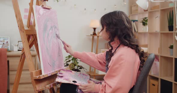 Side View of Young Creative Girl Making Modern Art Picture Using Spatula and Acrylic Paints