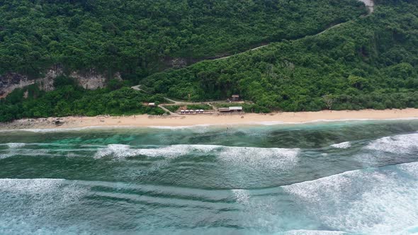 waves crashing onto Nyang Nyang Beach in Uluwatu Bali on cloudy day, aerial