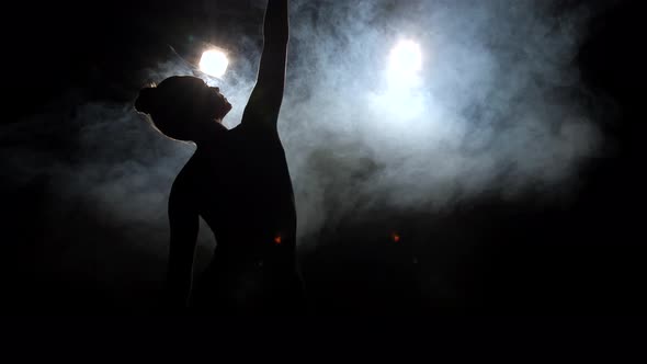 Silhouette of Young Dancer on Black Backlit Stage