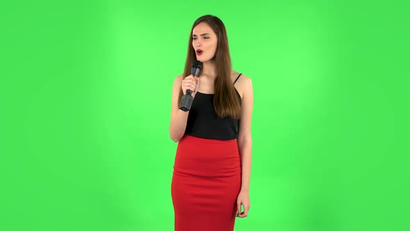 Attractive Girl Sings Into a Microphone and Moves To the Beat of Music. Green Screen