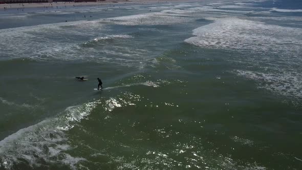 Drone shot of surfers at Muizenberg beach, Cape Town - drone is following a fliteboard surfer having