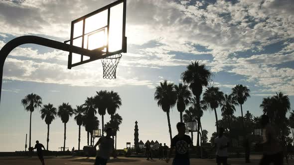 backlit shot of athletes playing street basketball