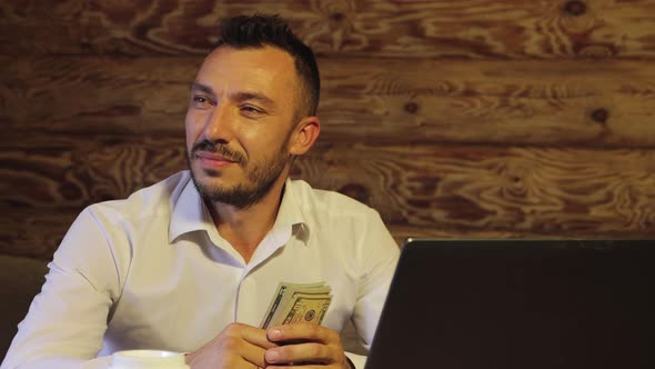 A Lucky Businessman is Holding Dollars and Looking at the Camera He is Happy