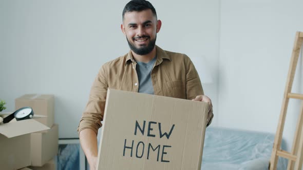 Slow Motion of Cheerful Mixed Race Man Holding Cardboard Box Standing in New Home