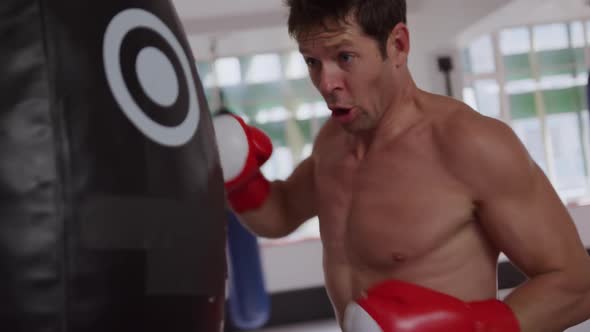 Caucasian man using punchbag in boxing gym