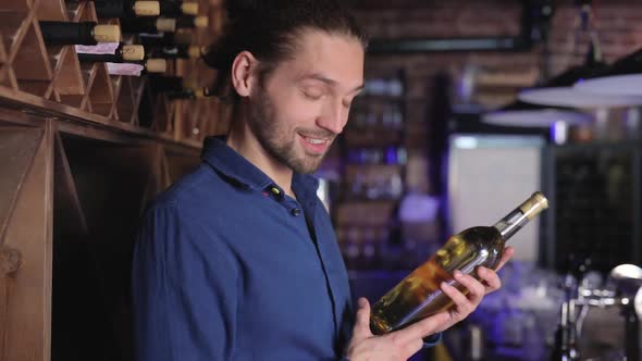 Handsome Man Holding Bottle Of Wine At Wine Cellar