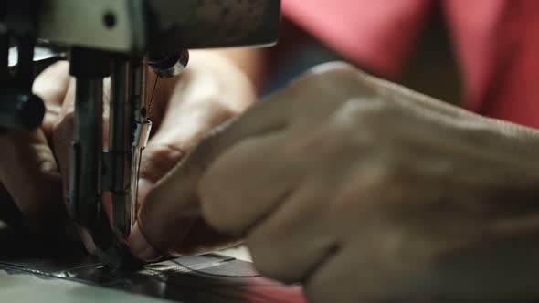 Close-Up Of Tailor Working On Sewing Machine in leather factory background