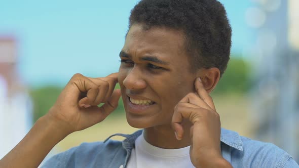 Teenage Boy Closing Ears From Pain