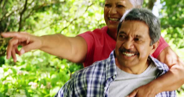 Senior man giving piggyback to woman in the park