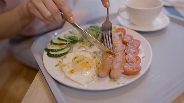 High Angle View of Female Hands Cutting Sausage on Plate in Restaurant or Cafe