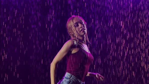 A Slender Blonde in Shorts and a T Shirt Is Enjoying Salsa Dance in the Pouring Rain. Young