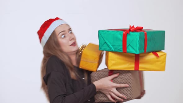 Young Beautiful Fairhaired Girl Dropping Stack of Gift Boxes Over White Background