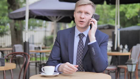 Businessman Talking on Phone While Relaxing Outdoor