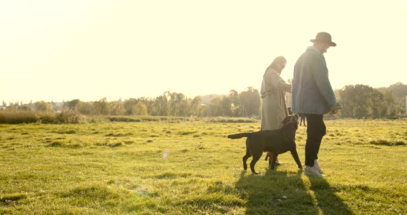 Young Man in Hat and Young Woman with Dog in Nature