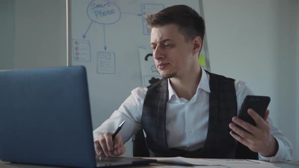 Ux Designer Working on Laptop, Checking His Phone and Drawing on Paper