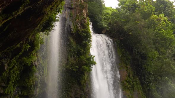 Camera pans down the powerful Nauyaca Waterfall in Costa Rica in slow motion