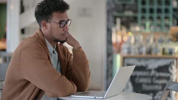 African Man Thinking While Using Laptop Cafe