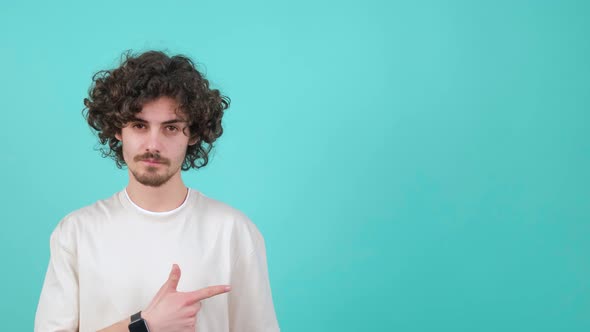 A Young Curly Haired Man is Pointing to the Left and Showing the Thumb Up Gesture