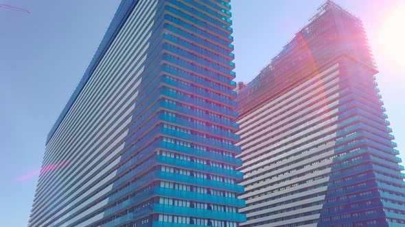 shot of reflections of sun, clouds and sky on glass windows of city skyscraper.