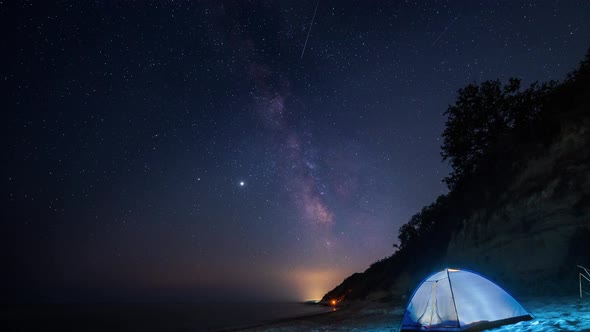 Time lapse with Milky Way galaxy and a tent at a sandy beach