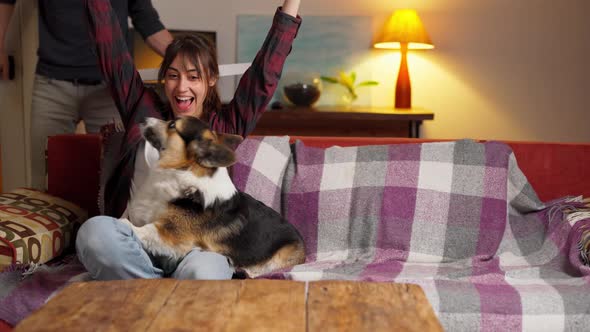 Woman with Dog Sitting on Couch While Man with Pizza Coming in Room