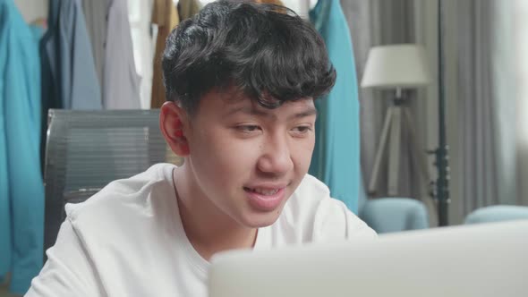 Close Up Of Asian Man Online Seller Looking At Computer Screen While Selling Clothes At Home